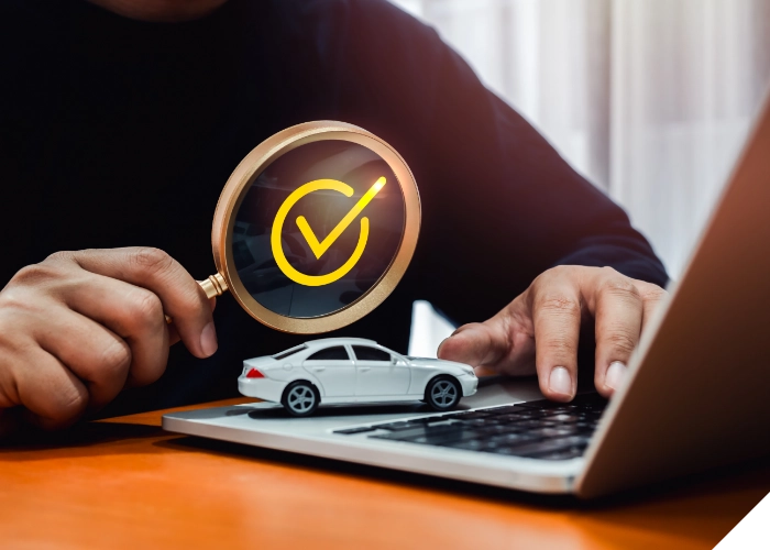 Symbolbild für geprüfte Fahrzeugsicherheit mit Lupe und Modellauto