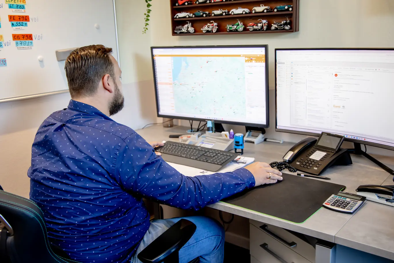 Mitarbeiter plant Fahrzeugtransporte für Autohäuser am Computer