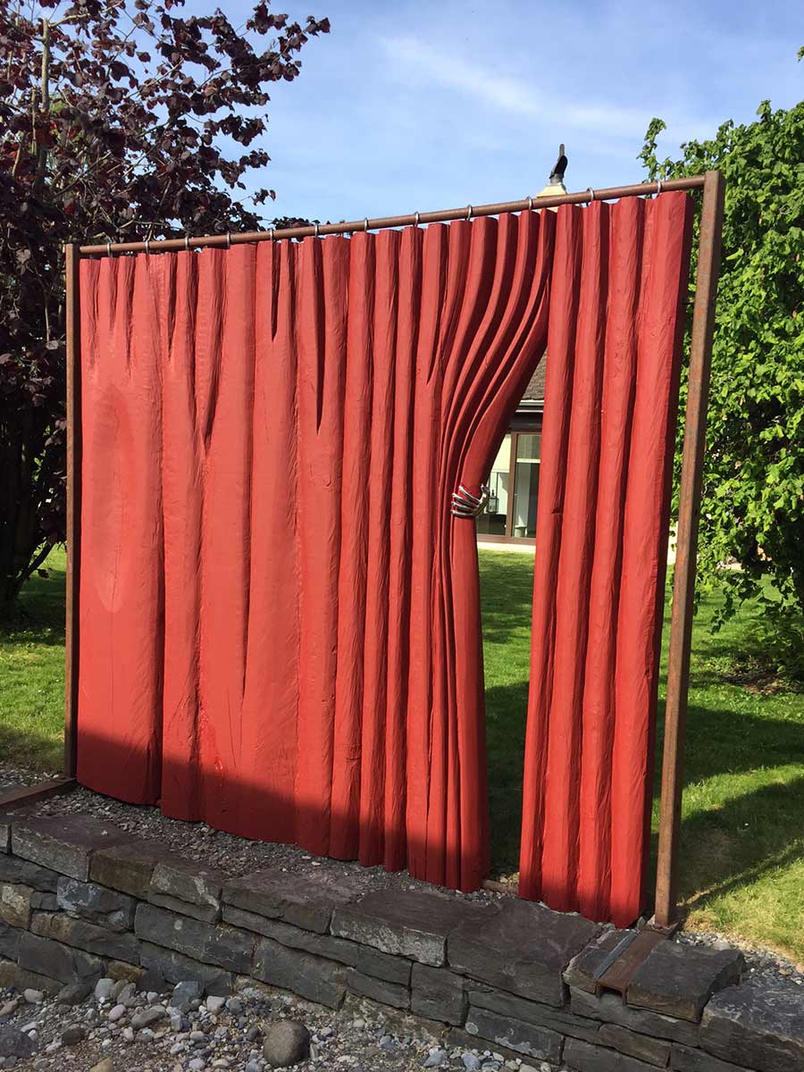 Roter Metallzaun mit einer realistisch wirkenden, zusammengezogenen Vorhangoptik, im Garten vor Bäumen und Rasen.