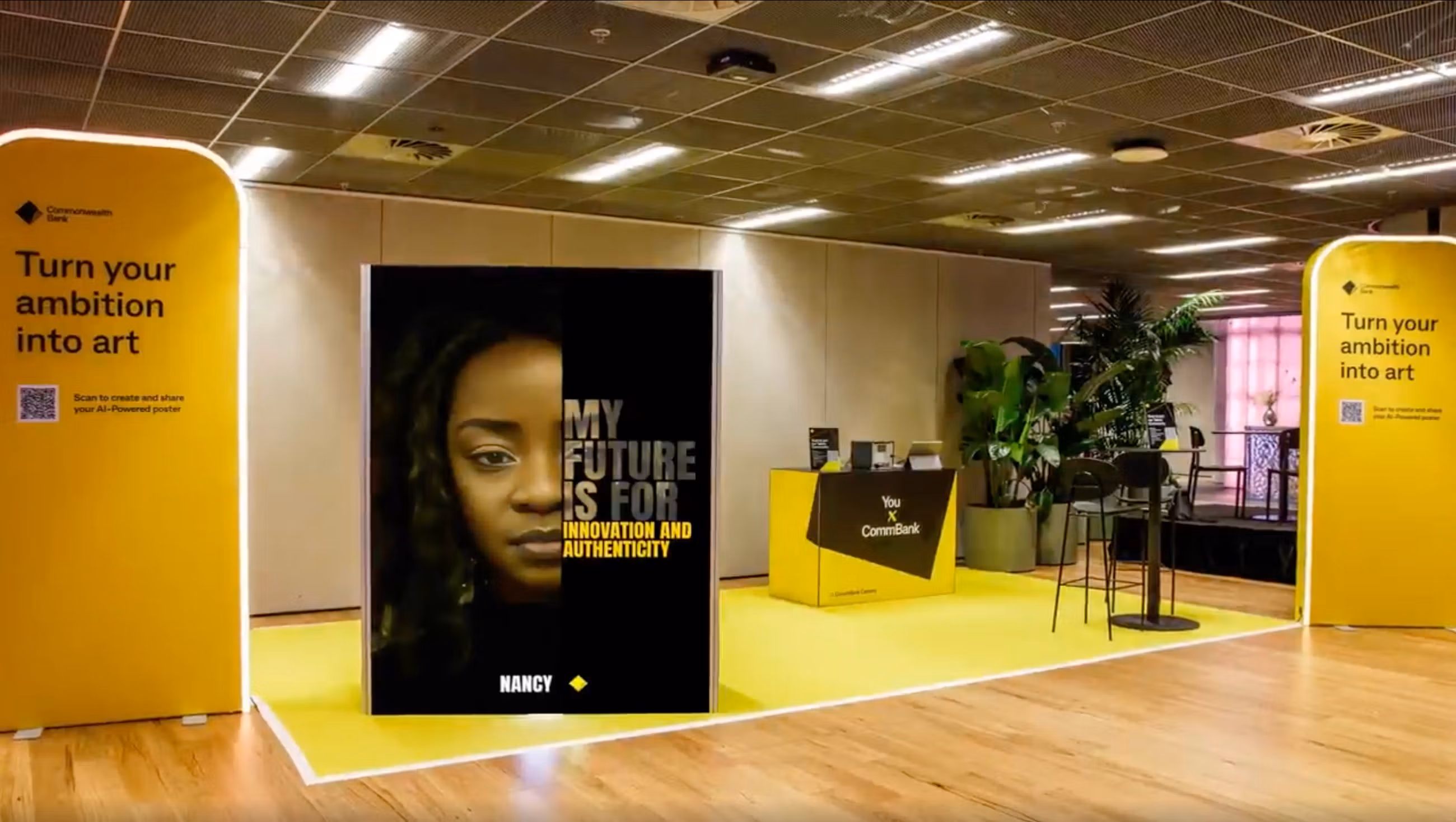 Yellow Commonwealth Bank AI Photo Booth featuring a large poster of Nancy and a QR code for AI-powered art