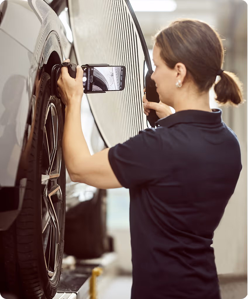 Mitarbeiterin untersucht einen Unfallschaden an der Fahrzeugseite für ein Unfallgutachten