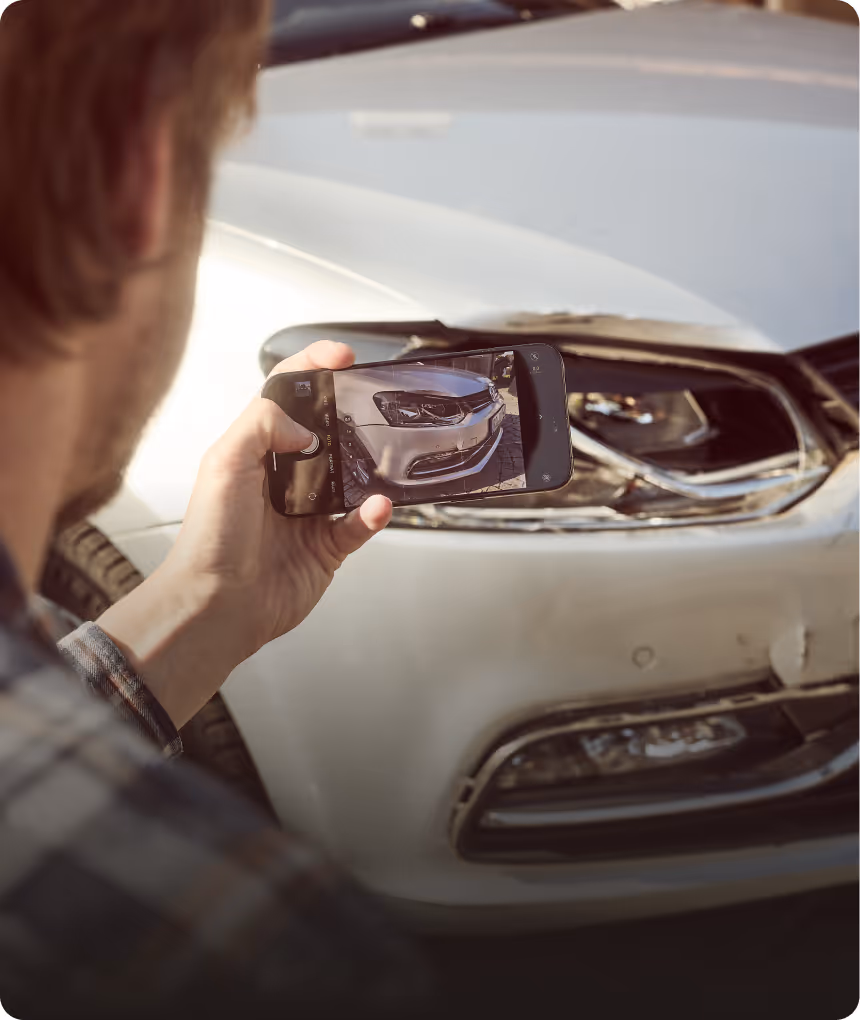 Kunde dokumentiert einen Kaskoschaden an einem Auto mit einen Handy
