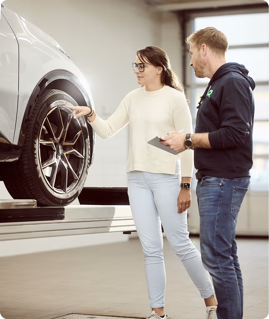 Mitarbeiter begutachtet gemeinsam mit einer Kundin einen Unfallschaden am Auto