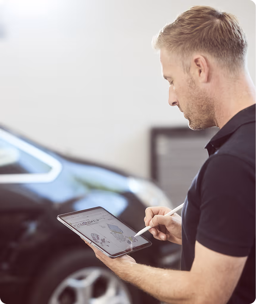 Mitarbeiter begutachtet ein Auto und dokumentiert Schaden in einem Ipad