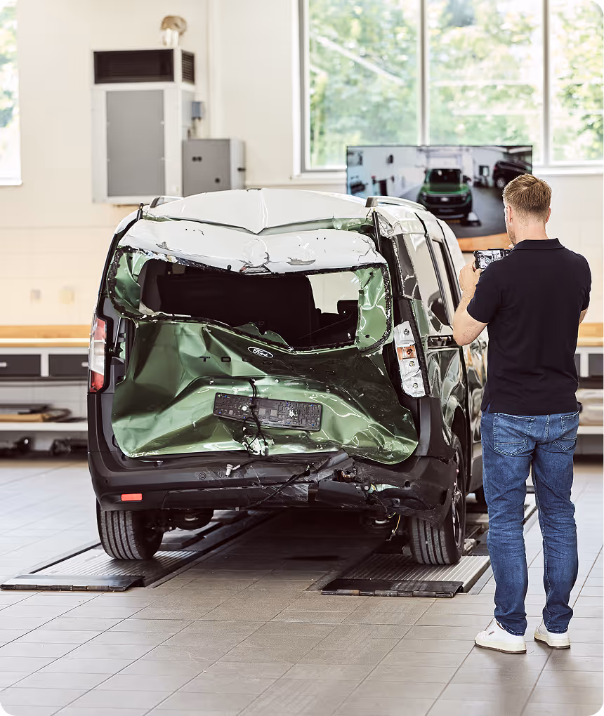 Mitarbeiter begutachtet einen Kaskoschaden an der Seite eines Autos in der Schadenprüfhalle