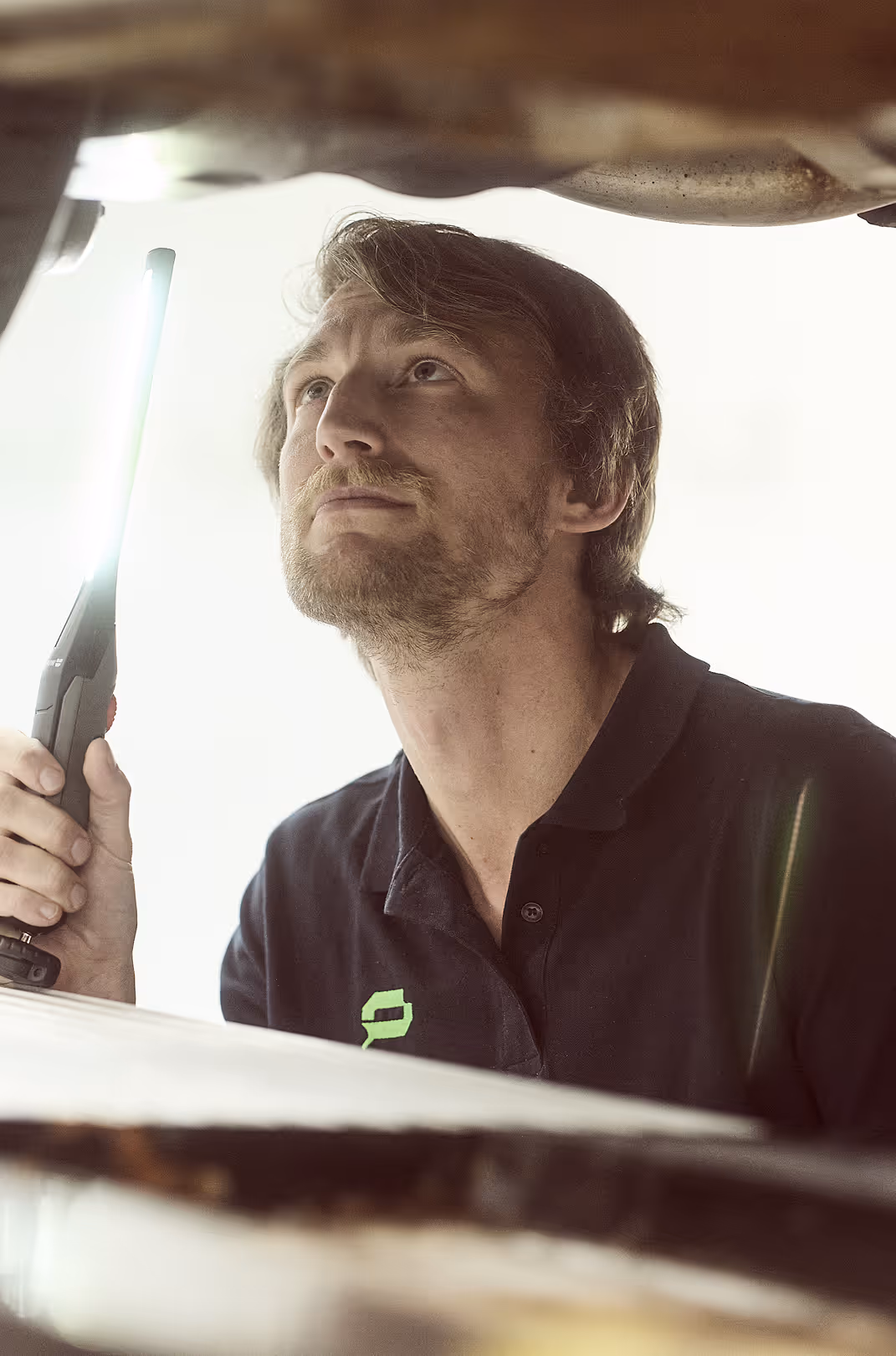 Ein Mitarbeiter führt eine Fahrzeugbewertung an einem Auto in der Schadenprüfhalle durch