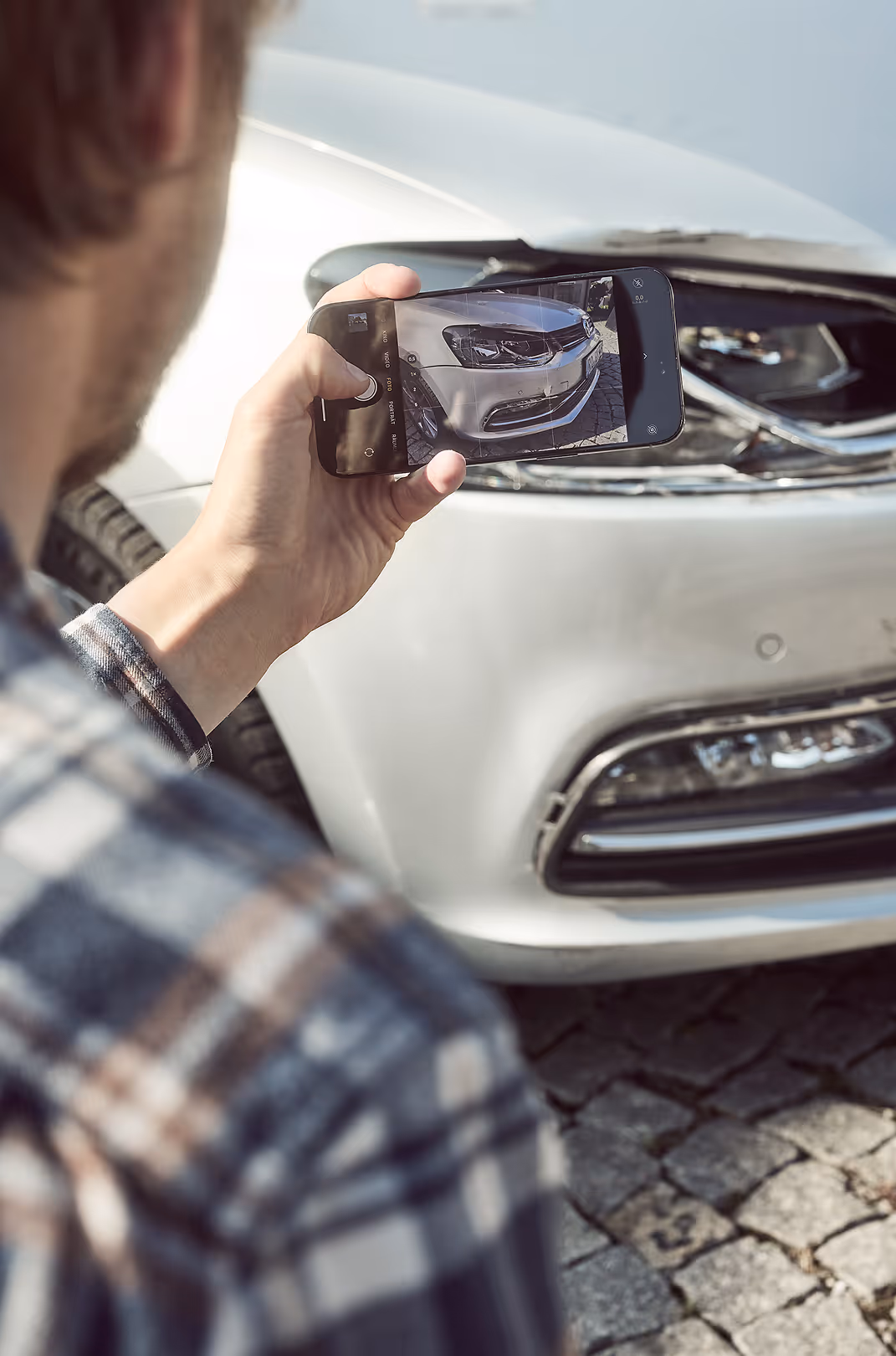 Kunde dokumentiert einen Kaskoschaden an einem Auto mit einen Handy