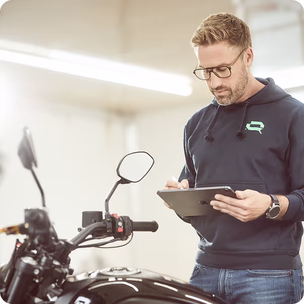 Geschäftsführer Jürgen begutachtet ein Motorrad in der Schadenprüfhalle