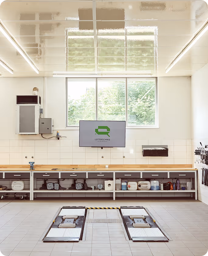 Helle Schadenprüfhalle mit  Fahrzeughebebühne zur genauen Begutachtung von Autos