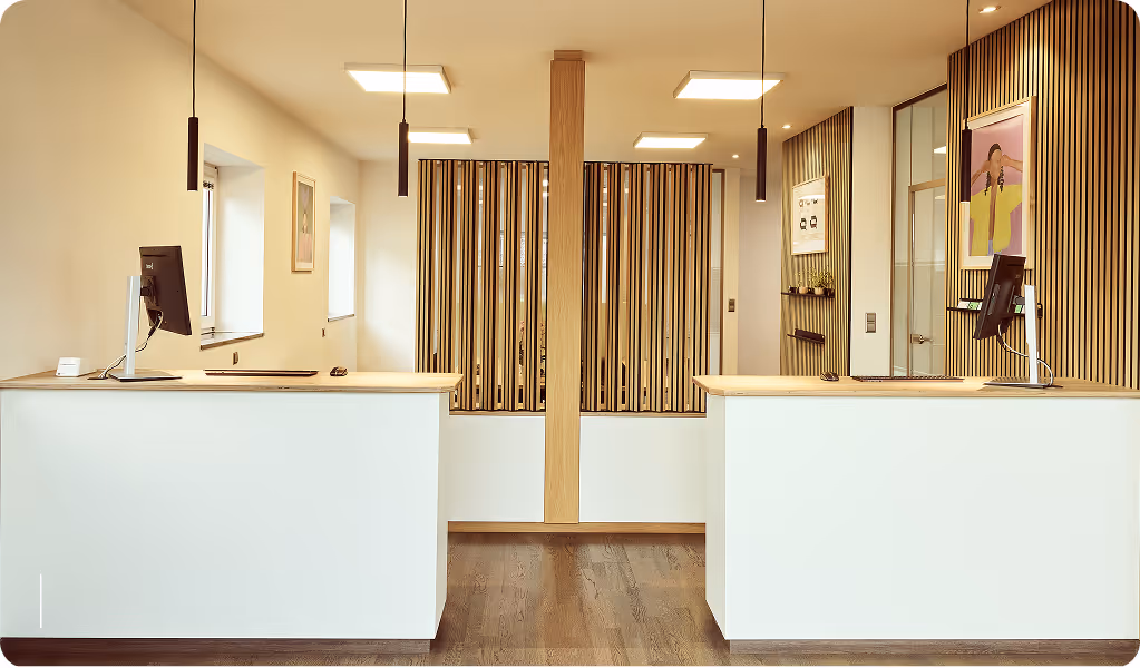 Eingangsbereich mit Theke aus hellem Holz, moderner Einrichtung und freundlicher Atmosphäre