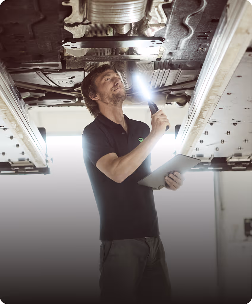 KFZ-Gutachter prüft den Unterboden eines Fahrzeugs auf der Hebebühne zur technischen Begutachtung.