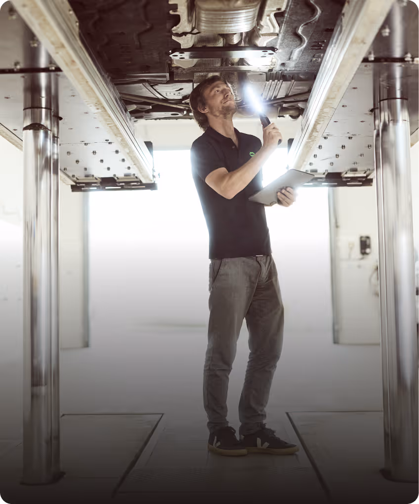 KFZ-Gutachter untersucht das Fahrzeug von unten auf der Hebebühne zur Erstellung eines technischen Gutachtens.