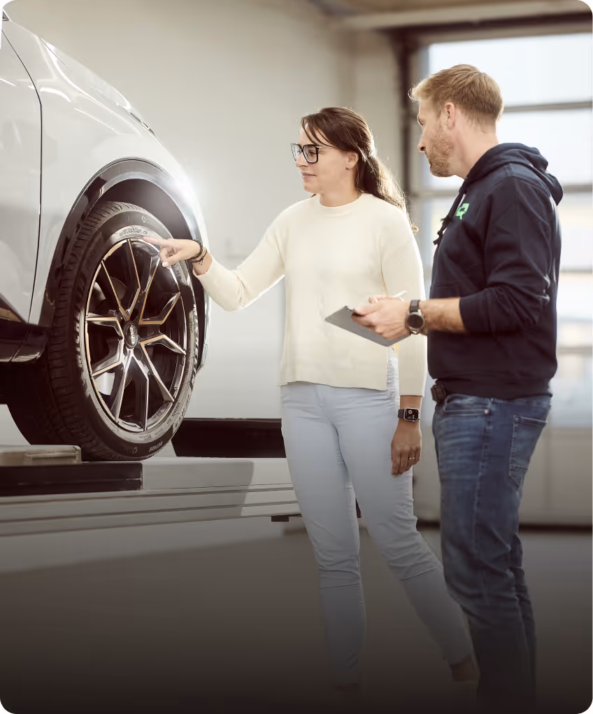 KFZ-Sachverständiger von Lotterschmid bespricht mit Kundin ein Unfallgutachten an einem Fahrzeug auf der Hebebühne