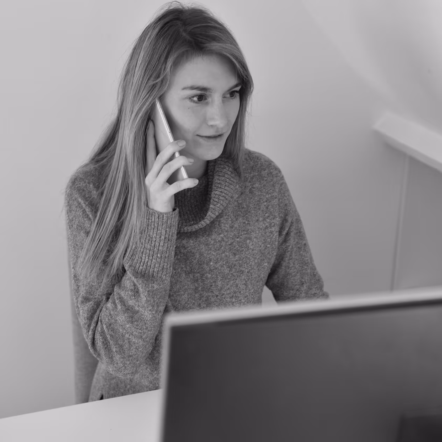 Woman on a cordless phone in front of her computer