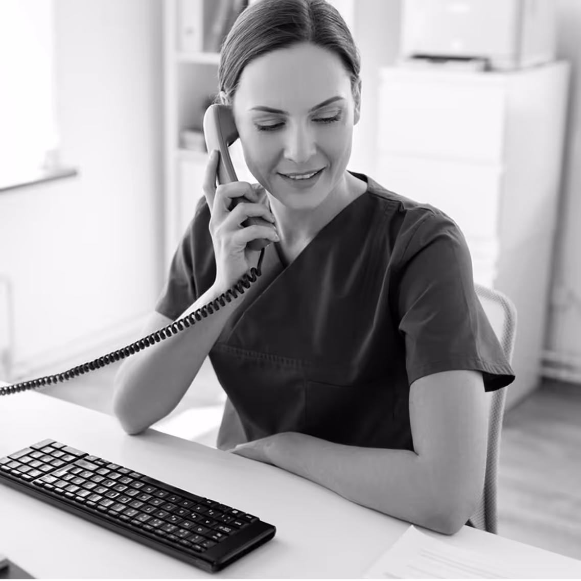 Healthcare administrator smiling on her desk phone