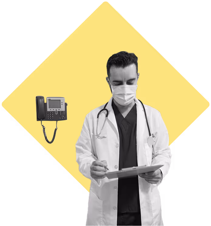 Doctor with a mask on, looking at charts with a wall mounted business phone in the background