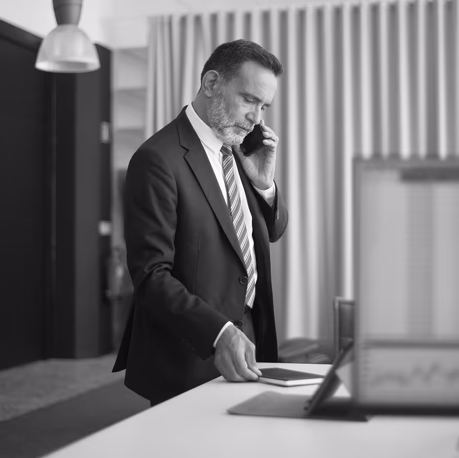 Man standing at his desk, on the phone