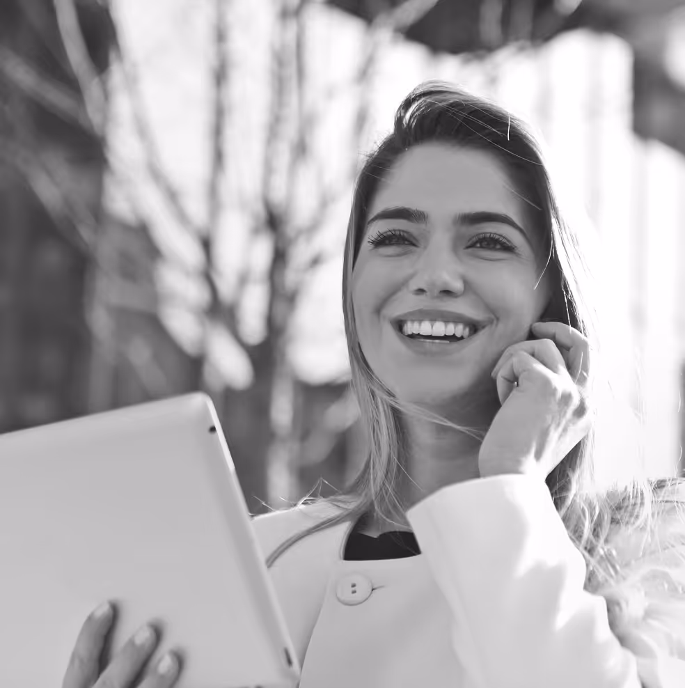Corporate woman smiling, speaking on her mobile business phone holding a tablet.