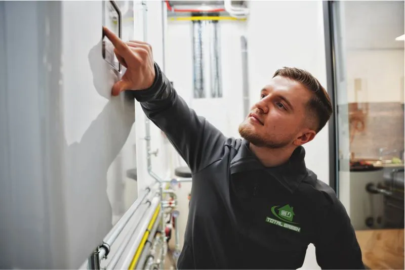 Een technicus van Toteco, gekleed in een bedrijfstrui, stelt een systeempaneel af in een moderne, goed uitgeruste technische ruimte.