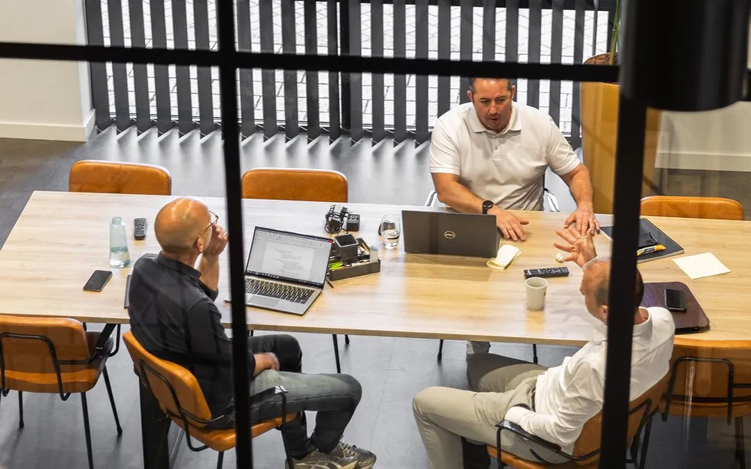 a group of men sitting around a table with laptops