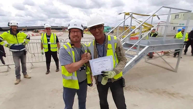 two men wearing safety vests and helmets holding a certificate