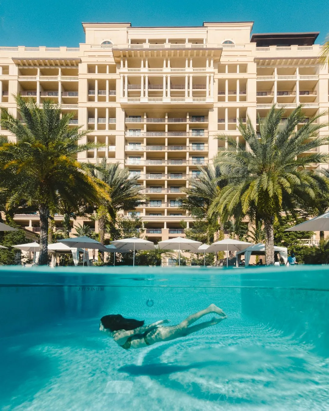 A woman swimming in a pool in front of a hotel.