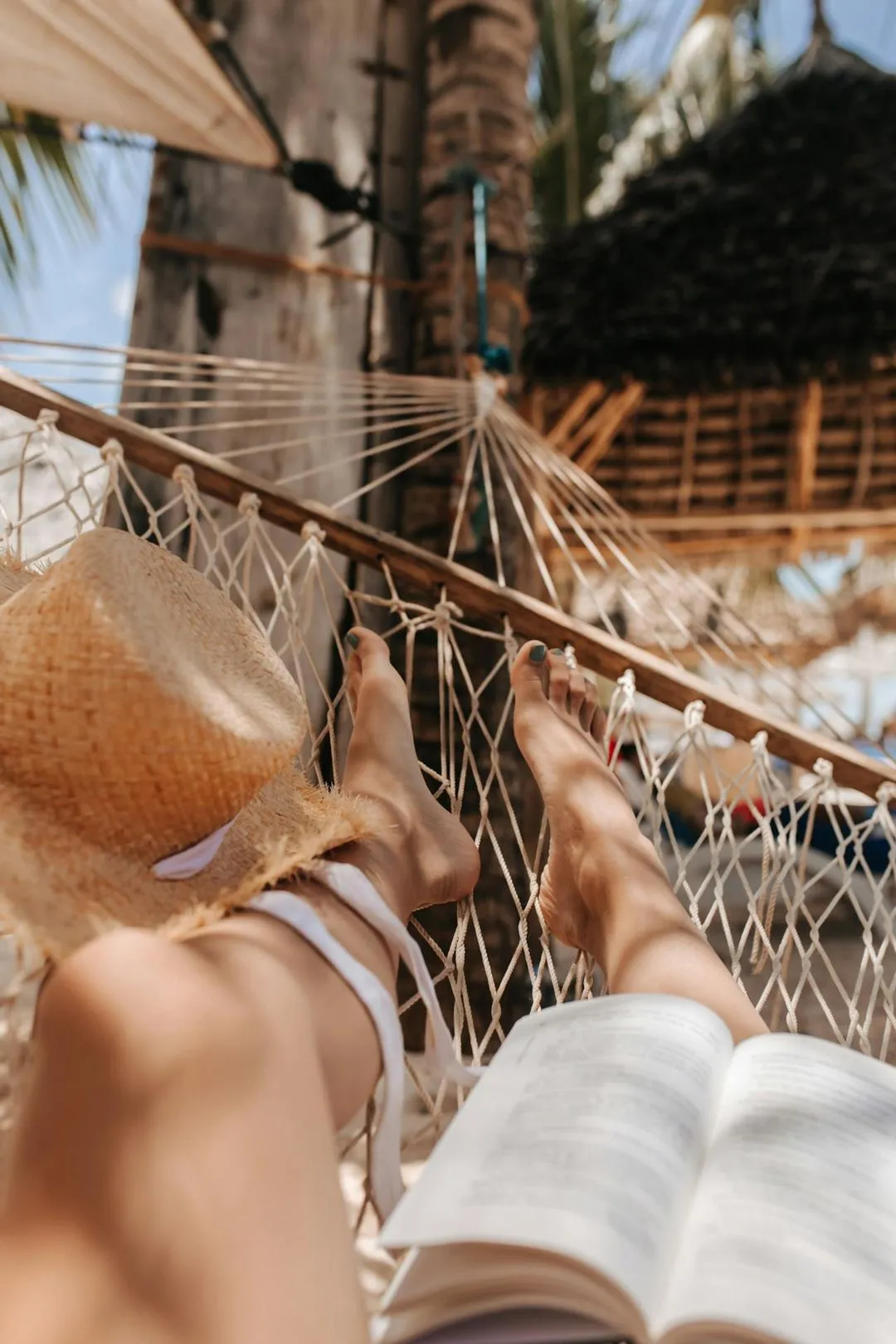 A person laying in a hammock reading a book.