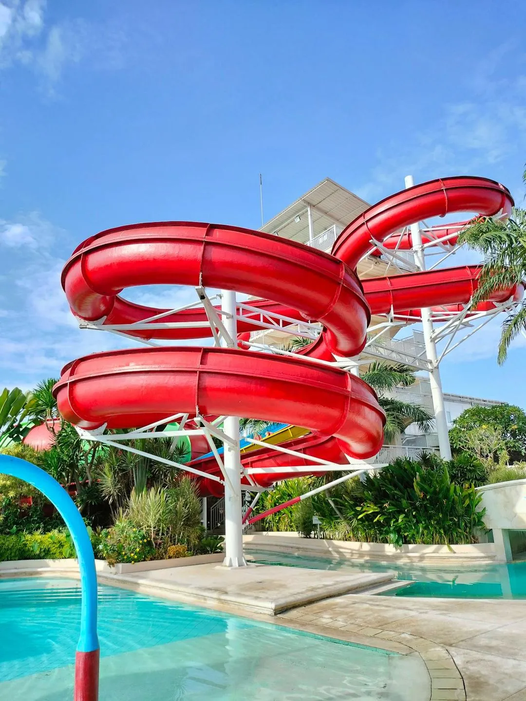 A red water slide next to a swimming pool.