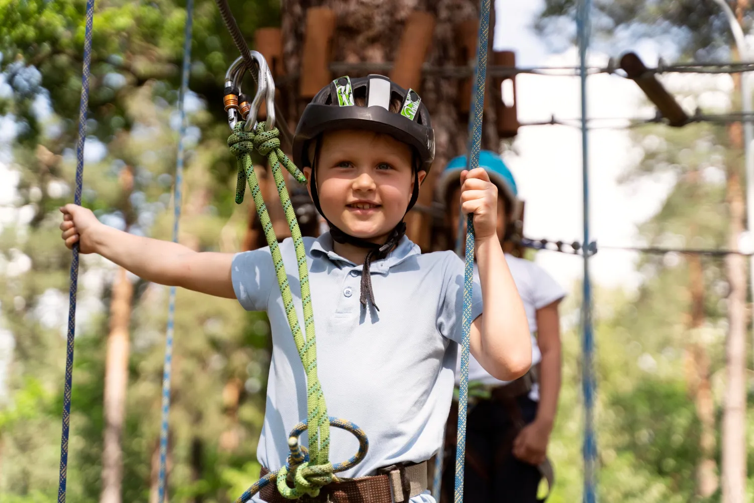 A young boy wearing a helmet and holding onto a rope.