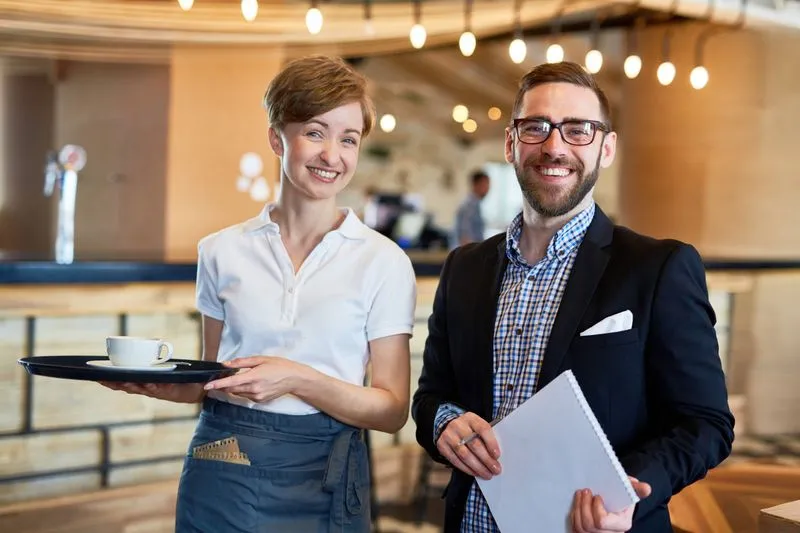 A man and a woman holding a tray of food.