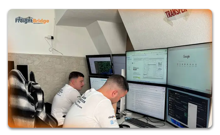 Freight coordinator with headset tracking shipments on multi-screen setup in port-side office with containers – FreightBridge