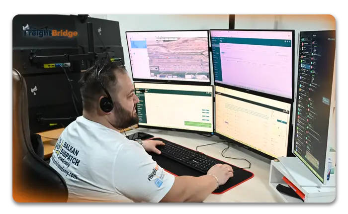 Logistics analyst reviews shipping data on dual monitors in port-side office with container cranes and cargo ship in background – FreightBridge