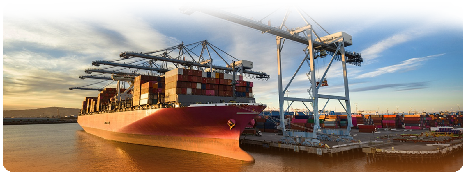 Cargo ship docked at a port under container cranes during golden hour, representing global logistics.