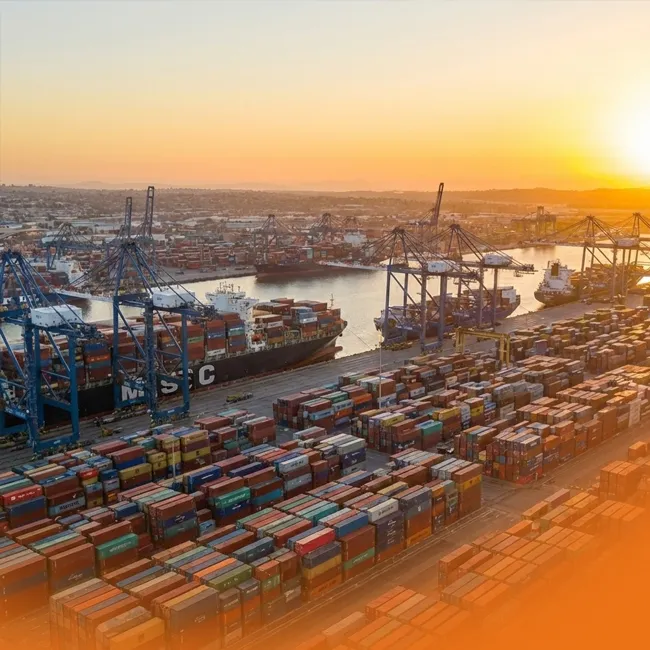 Aerial view of the Port of Los Angeles at sunset, densely packed with colorful shipping containers and massive cargo ships, illustrating the potential to hit a 10 million TEU record.