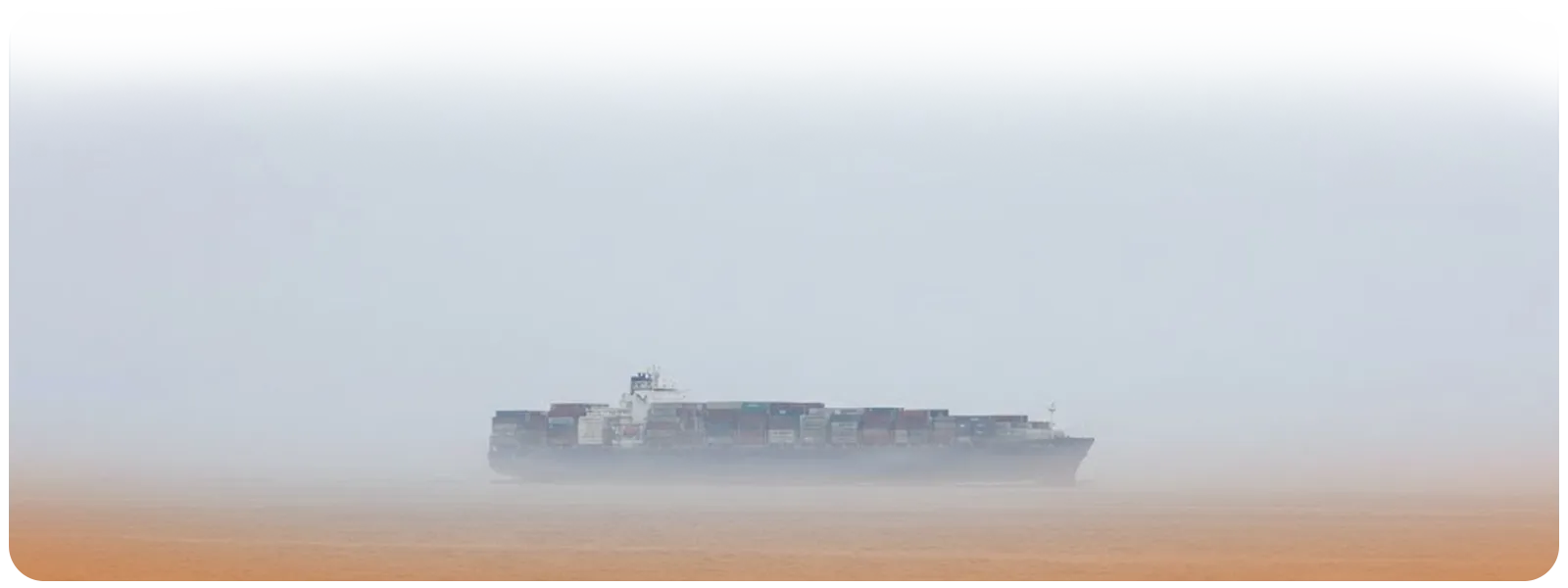 Wide image of container ship sailing through heavy fog, symbolizing weakening Transpacific spot rates.