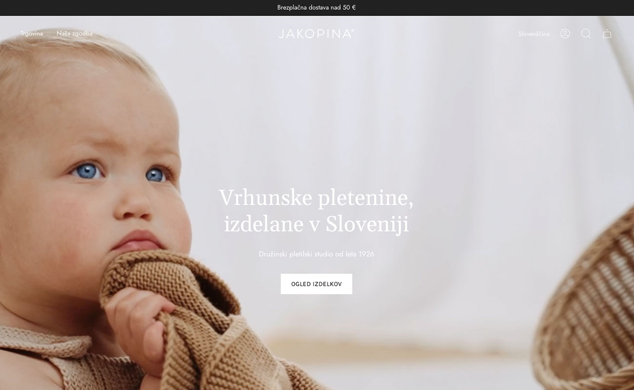 Close-up of a baby with blue eyes holding a brown knitted garment.