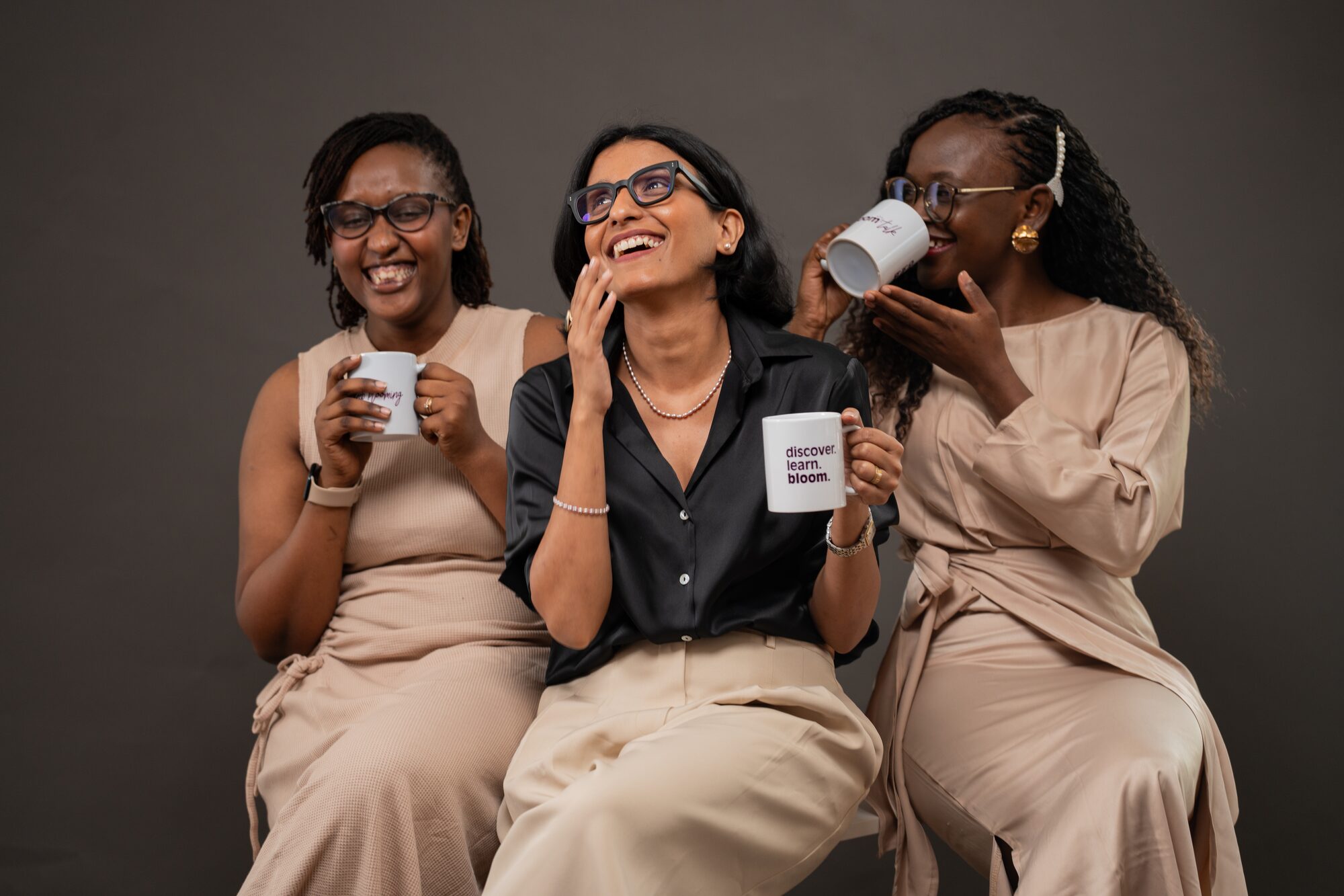 Three Maple Bloom staff members laughing together with branded mugs