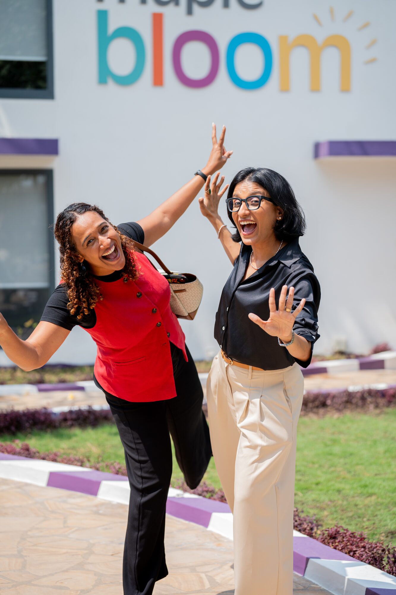 Two Maple Bloom staff members celebrating outside the school building