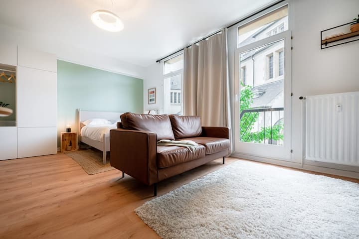 Bed and sitting area with natural light in renovated studio