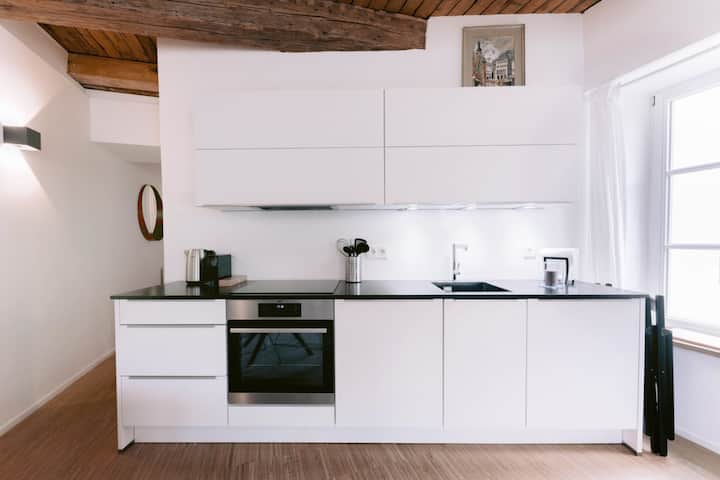 Open-plan kitchen with oven, induction hob and white cabinetry, 1BR Old Town Luxembourg