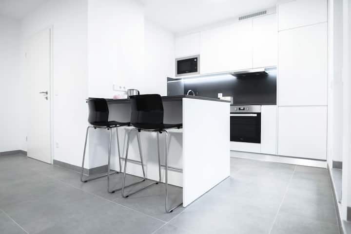 Cozinha com península e bancos altos, bancada branca