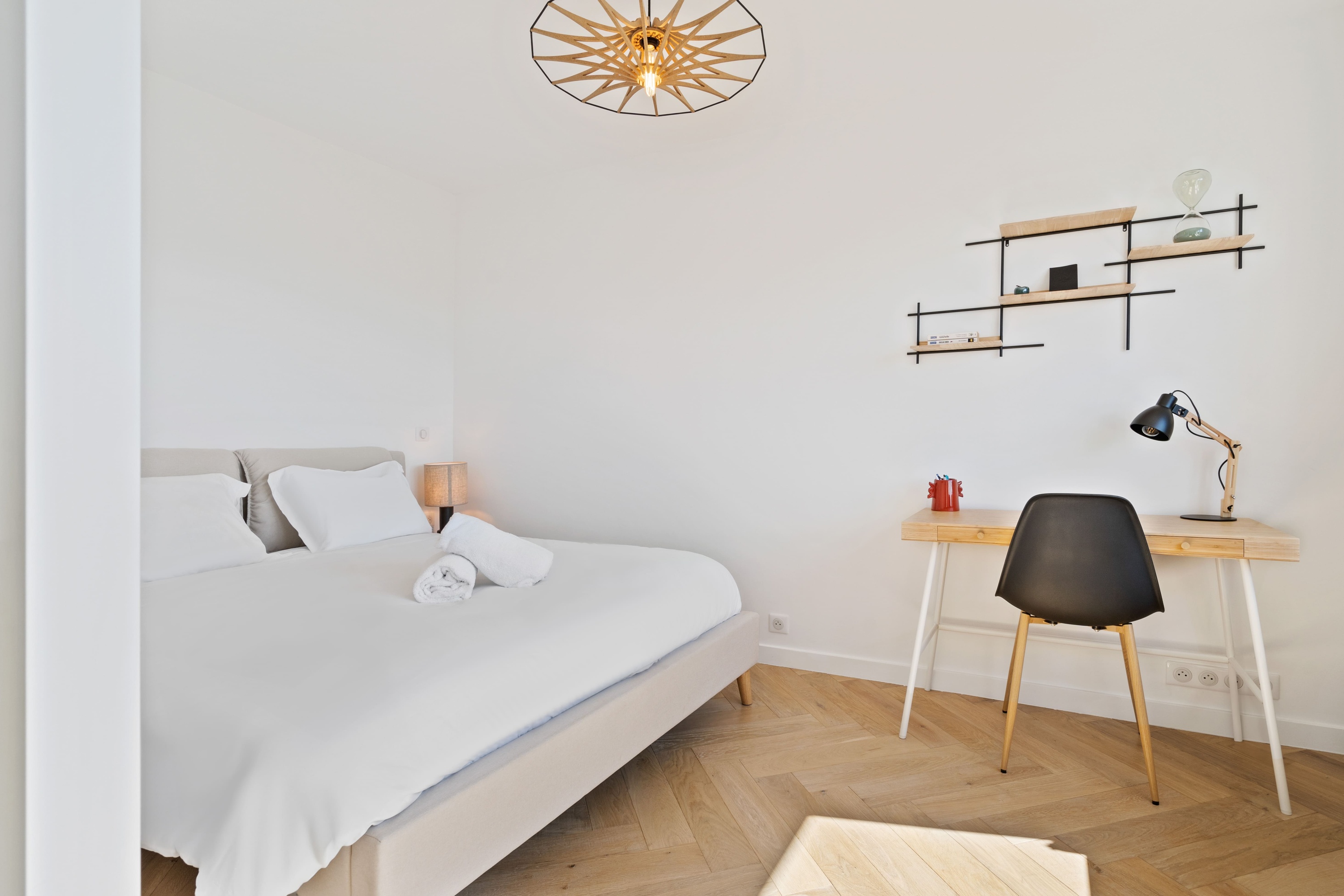 Bedroom zone with white bed and pendant light, bright neutral decor