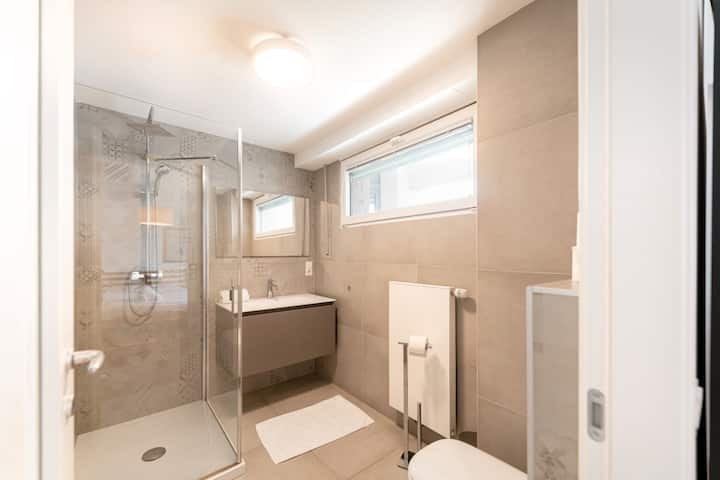 Bathroom with vanity, mirror and window, neutral tiles
