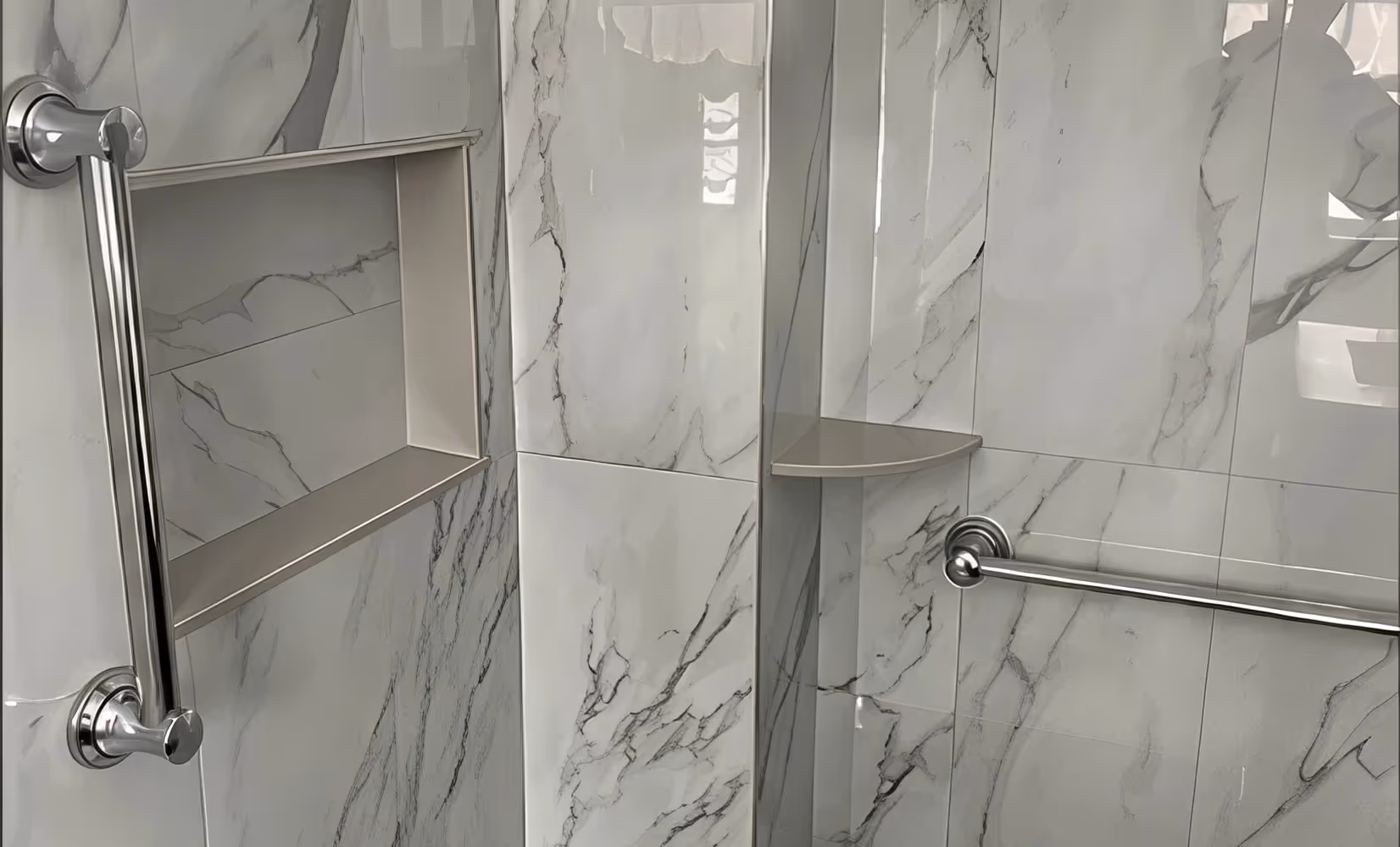 Modern shower with gray marble shower tile, grab bars, a built-in shelf, and a corner soap holder.