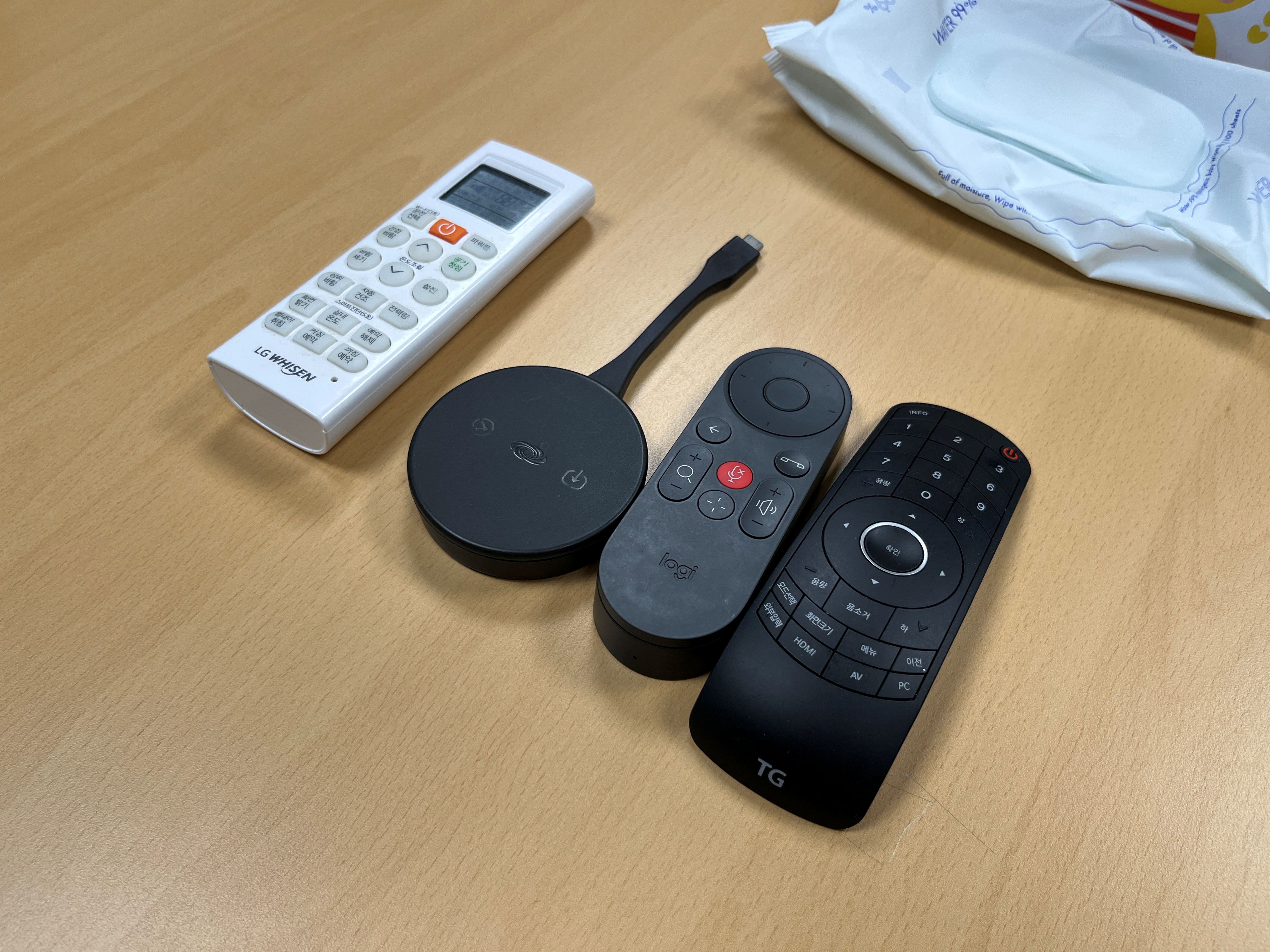 테이블 위 AirMedia AM-TX3-100 동글과 Logitech 리모컨