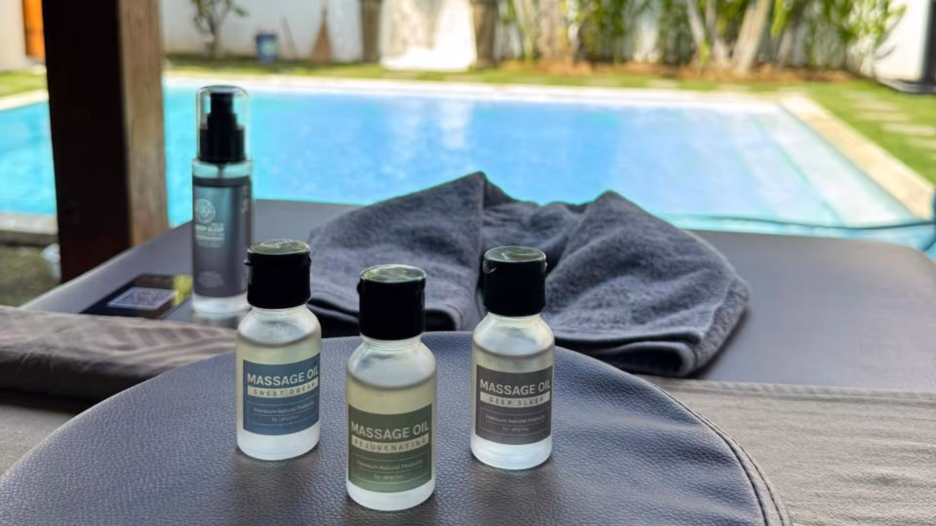 a selection of natural massage oils prepared on a massage bed by the poolside, ready to be used for a treatment session.