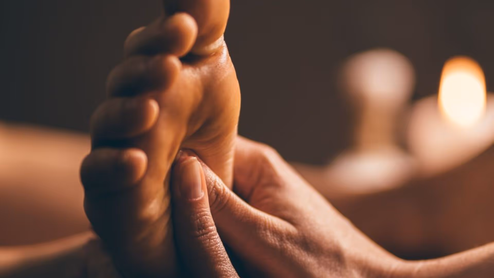 a therapist giving a foot massage, applying pressure to a specific point on the sole of a client's foot in a calm setting.