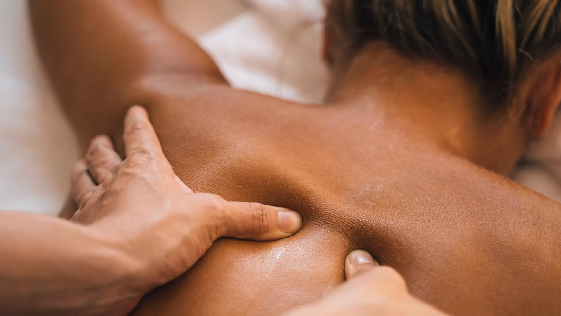 A therapist is applying deep, focused pressure to a client's back