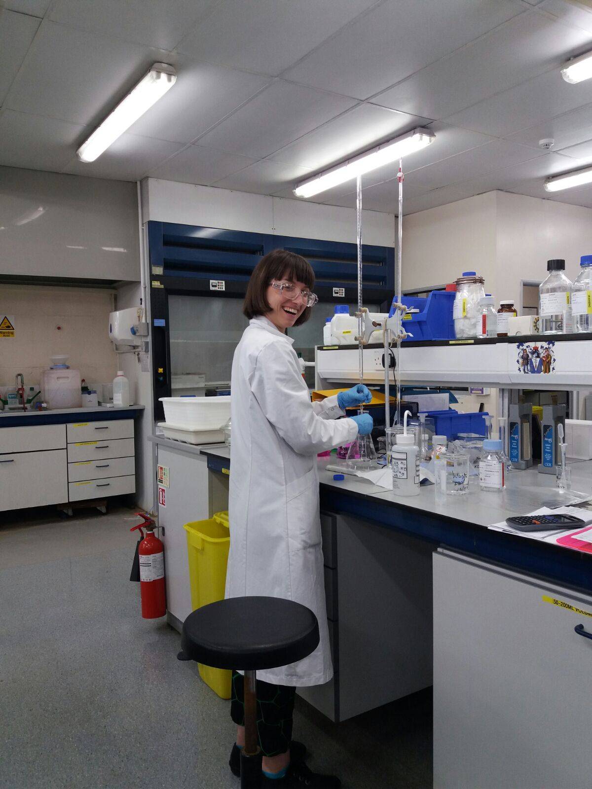 Image of Konnie in a lab, mixing a chemical solution and lauging at the camera