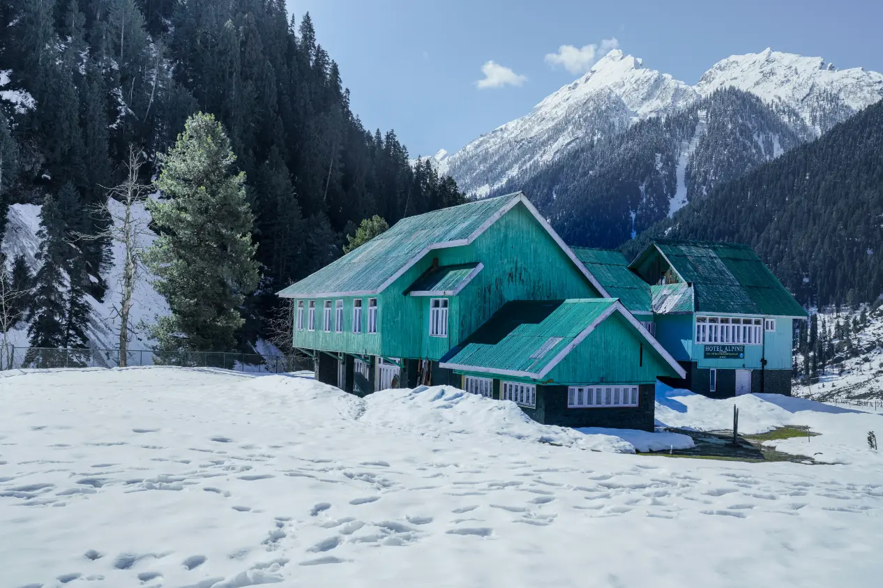 Mountain lodge surrounded by snow-covered peaks in Kashmir during winter